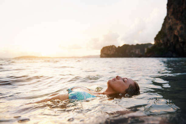 Just go with the flow Shot of a woman floating on her back in the ocean floating on water stock pictures, royalty-free photos & images