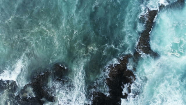 Aerial Slow Motion Shot Of Waves Rushing Towards Rocky Shore