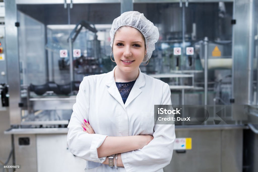 Water bottling factory interiors and machinery. Young happy woman worker in factory checking water bottles or gallons before shipment. Inspection quality control. People at work. Occupation Stock Photo