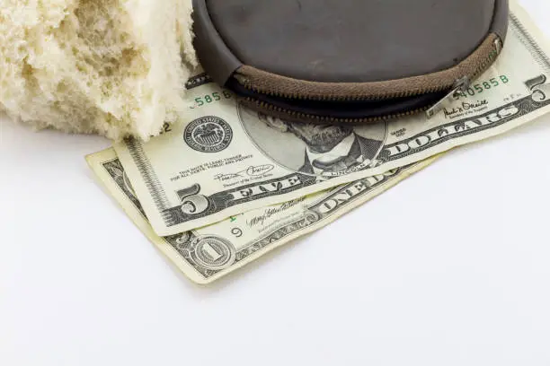 Old wallet / purse with dollar notes and a crust of bread on white background - conceptual image depicting poverty bread line in America - economic crises