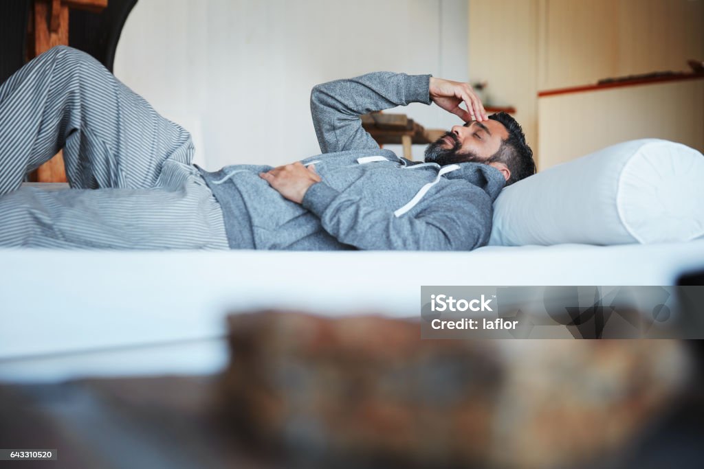 I can only take so much Shot of a mature man lying on his bed feeling exhausted Men Stock Photo