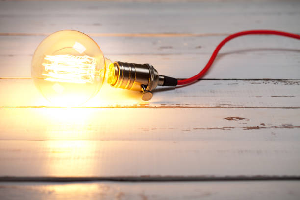 istock Vintage incandescent Edison type bulb on white wooden table 643317104