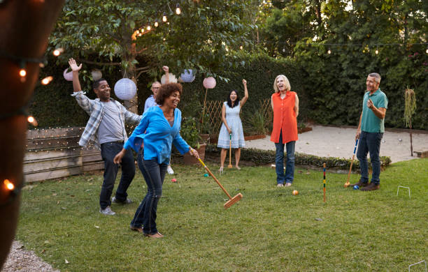 gruppo di amici maturi che giocano a croquet nel cortile di casa insieme - festa in giardino foto e immagini stock