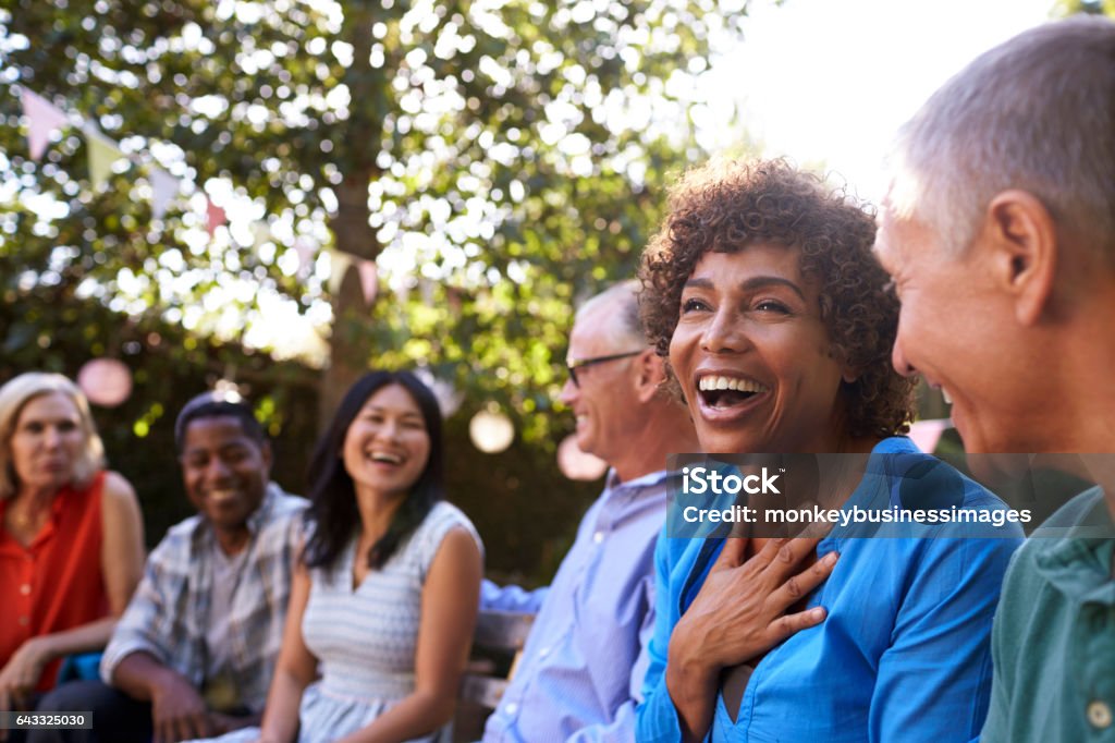 Gruppo di amici maturi che socializzano insieme nel cortile di casa - Foto stock royalty-free di Gruppo multietnico