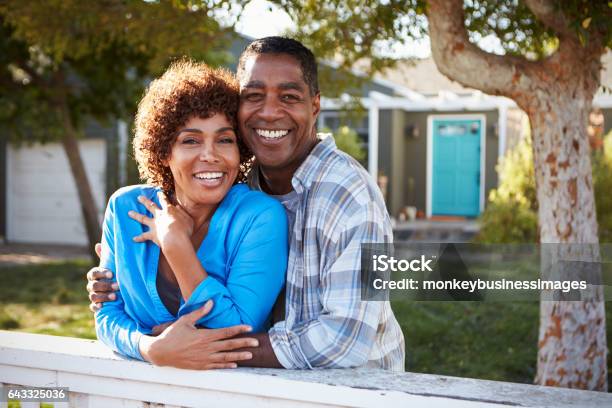 Retrato De Pareja Mirando Por Encima De La Cerca Del Patio Trasero Foto de stock y más banco de imágenes de Parejas