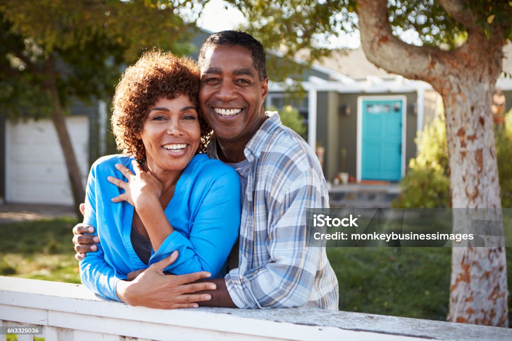Portrait Of Mature Couple Looking Over Back Yard Fence Couple - Relationship Stock Photo