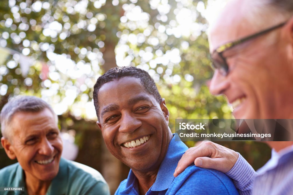 Mature Male Friends Socializing In Backyard Together Men Stock Photo