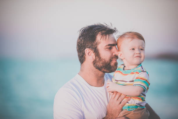 istock Dad Holding Baby Boy at Beach Sunset 643342024