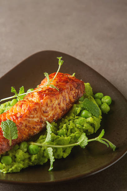 istock Grilled salmon pea puree decorated with mint on a brown plate. G 643342818