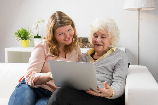 istock Granddaughter teaching grandma how to use laptop computer 643345532