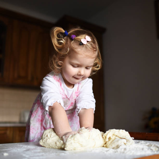 pretty little girl having fun kneads dough