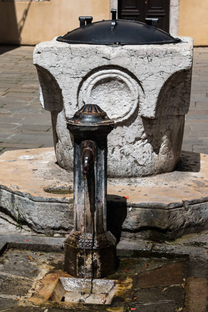 public iron fountain beside marble artesian well in venice, italy - well fountain water pipe pipe imagens e fotografias de stock