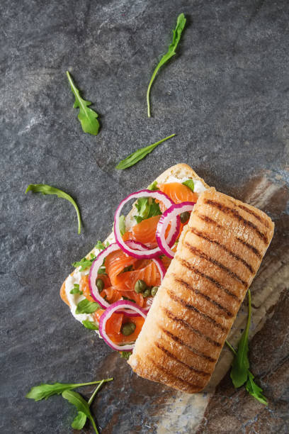 homemade baguette with smoked salmon, onions and arugula. dark b - 12007 imagens e fotografias de stock