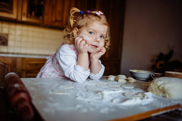 istock baker girl in chef hat at kitchen 643351020