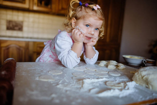 istock baker girl in chef hat at kitchen 643351196