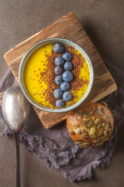 istock yellow smoothie. Soup with berries blueberry. Bread, Gray Backgr 643355180