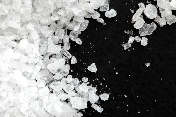 istock Closeup of coarse salt crystals on black from above. 643357482