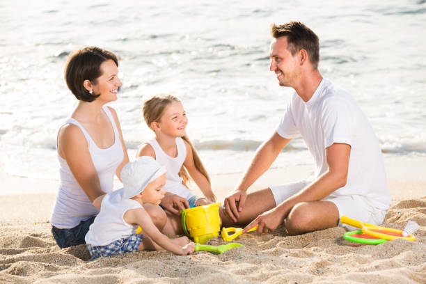 istock Glad family with two children playing at beach 643358358