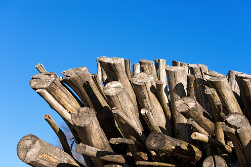 Dry firewood logs in a pile on blue clear sky