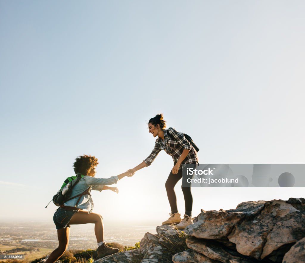 Amis de randonnée s’entraider dans les montagnes - Photo de Femmes libre de droits