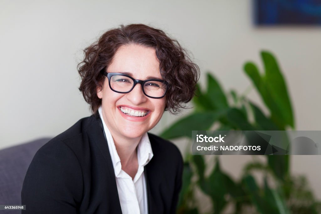 Spanish Businesswoman Smiling At the Camera. At the office. 40s,beauty, business, businesswoman, ceo, cheerful, closeup, confidence, cute, entrepreneur, eyeglasses, females, freshness, horizontal, laughing, leadership, lifestyles, office, people, portrait, purity, relaxation, secretary, sensuality, smiling, telecommuting, women, 40-49 years, brown hair, business person, caucasian ethnicity, copy space, customer service representative, fashion model, green eyes, head and shoulders, healthy lifestyle, home interior, human face, italian culture, one mid adult woman only, one person, professional occupation, serene people, spanish culture, toothy smile, tranquil scene Headshot Stock Photo