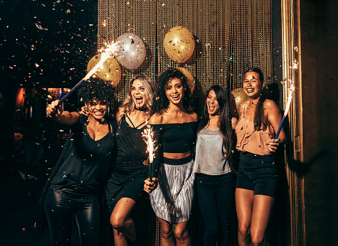 Shot of group of young women celebrating new years eve at the pub. Group of female friends with sparklers partying in nightclub.