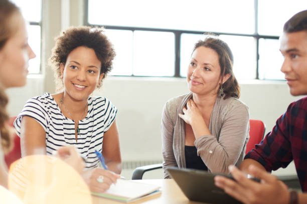 Unposed group of creative business entrepreneurs in an open concept office brainstorming together on a digital tablet