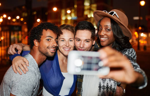 플래시를 사용 하 여 밤 시간에는 옥상 테라스에 휴대 전화와 함께 selfie 사진을 복용 하는 친구의 다민족 millenial 그룹 - team meeting flash 뉴스 사진 이미지