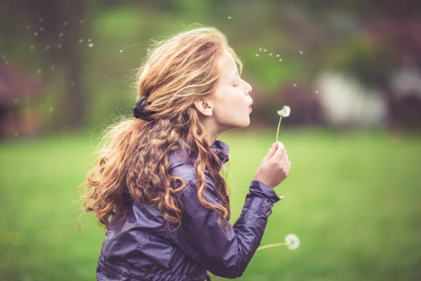 istock Girl in the field blowing a dandelion 643372548