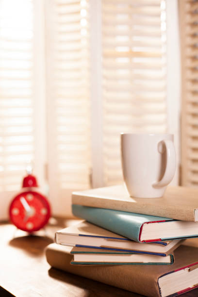 istock Stack of books on desk with coffee, alarm clock. 643376056