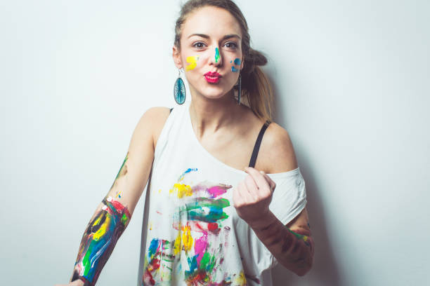 Crazy playful artist Woman having fun while painting her hands shirt and face with watercolors artists palette photos stock pictures, royalty-free photos & images