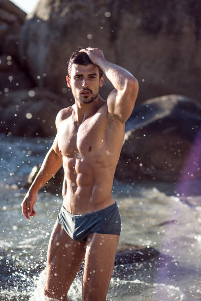 posrtrait of a handsome ripped young man close up of a handsome fit young man at the beach on a nice sunny day man muscular chest stock pictures, royalty-free photos & images