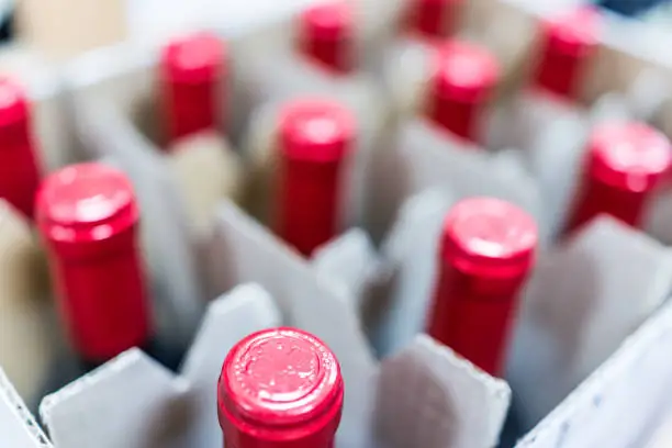 Tops of many red wine bottles separated in box