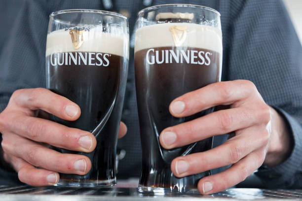 기네스 맥주를 들고 손 - guinness 뉴스 사진 이미지