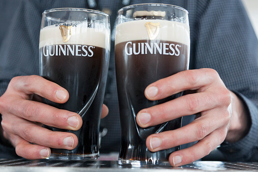 Dublin, Ireland - May 22, 2016.  Close up of a hands holding two cold pints of Guinness.
