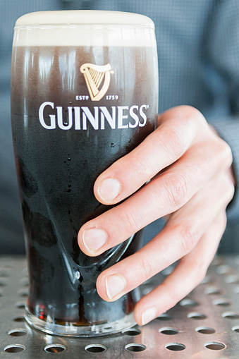 Dublin, Ireland - May 22, 2016.  Close up of a hand holding a cold pint of Guinness.