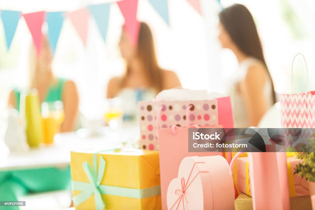 Presents Stack of various baby shower or birthday presents, people celebrating in the background. Baby Shower Stock Photo