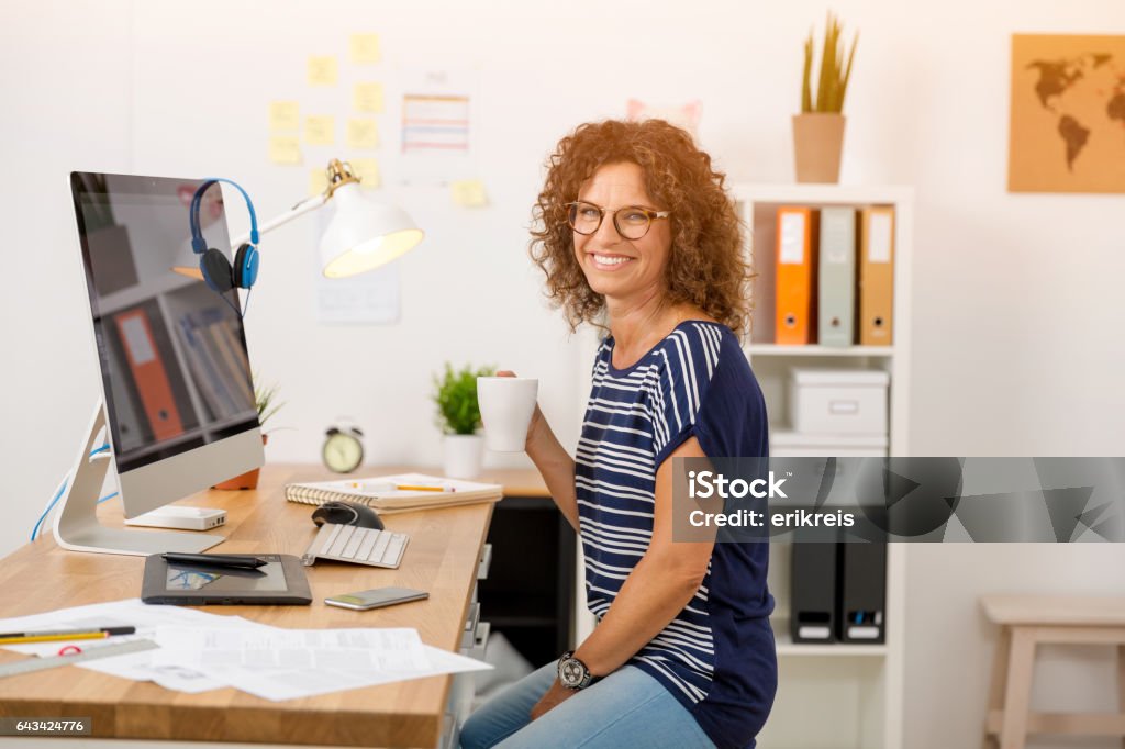 Coffee break at work Middle aged woman working on the office and drinking coffee Freelance Work Stock Photo