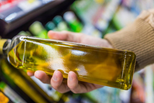istock Man holding a bottle of light yellow olive oil 643435520