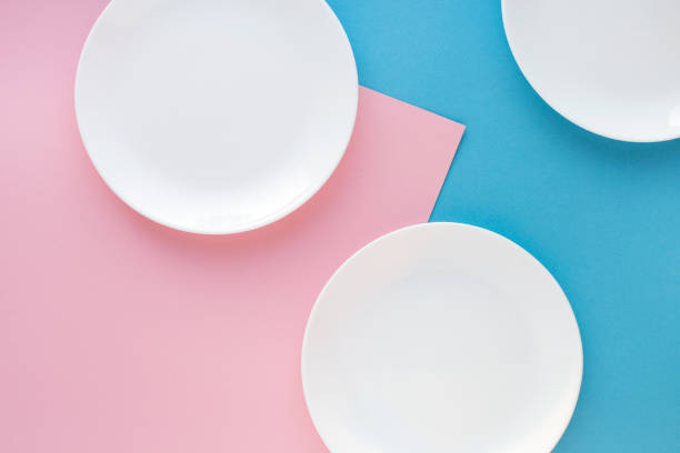 istock Three white plates on color background. Abstract, top view. 643449790