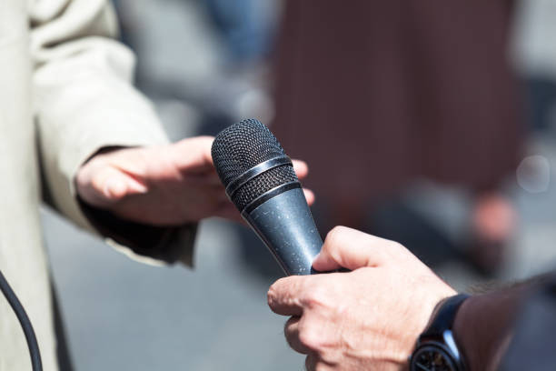 istock Journalist holding a microphone, conducting an TV or radio interview 643452914