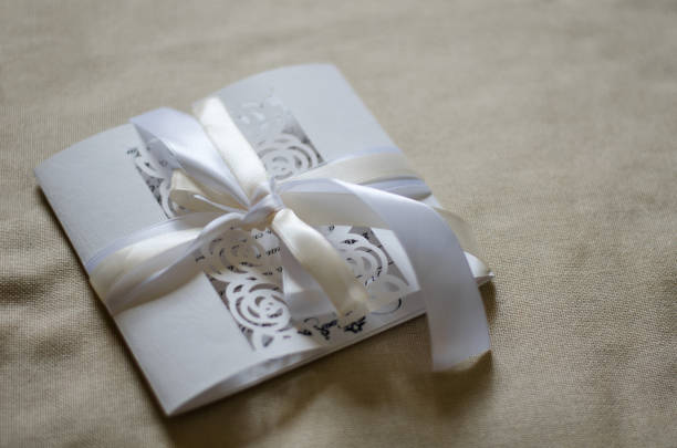 istock White openwork postcard with a satin ribbon on a beige background of textile 643456712