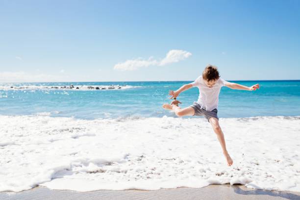 istock Happy 7 years boy jumping on the beach 643456758