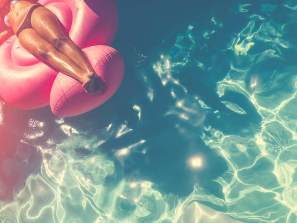 istock Woman floating on a pink inflatable in swimming pool. 643457654