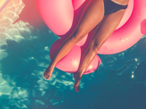 istock Woman floating on a pink inflatable in swimming pool. 643457662