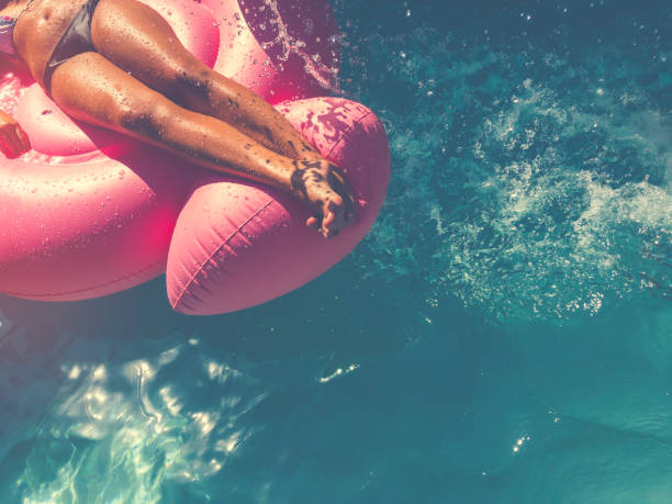 istock Woman floating on a pink inflatable in swimming pool. 643457664