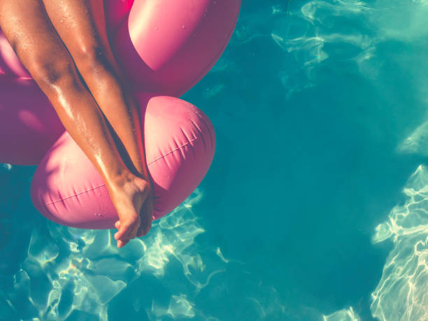 mujer flotando en un inflable color rosa en la piscina. - human leg smooth human skin human foot fotografías e imágenes de stock