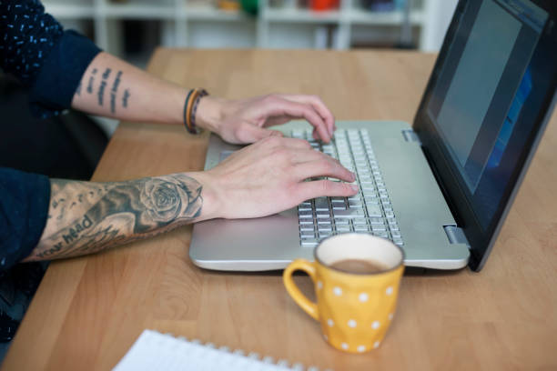 istock Man hands with tattoo working on laptop 643466456