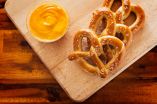 pretzels and dipping cheese on wood cutting board overhead