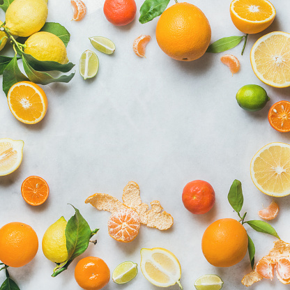 Variety of fresh citrus fruit for making juice or smoothie over light grey marble table background, top view, copy space, square crop. Healthy eating, vitamin, detox, diet food, clean eating concept